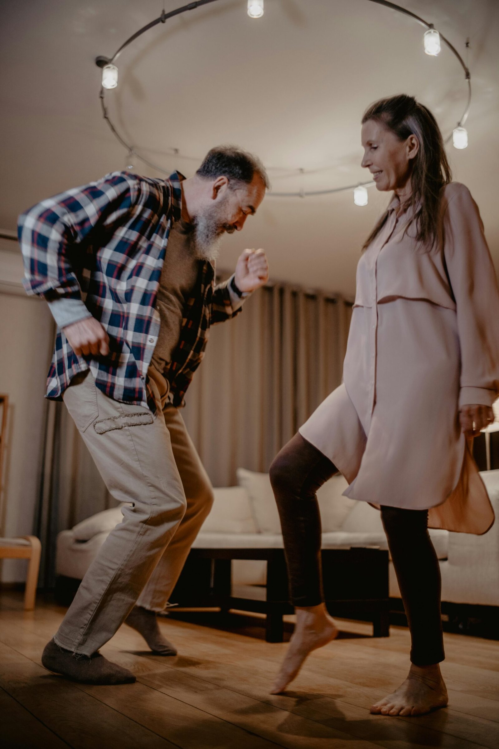 Happy elderly couple enjoying a dance together in their cozy living room.